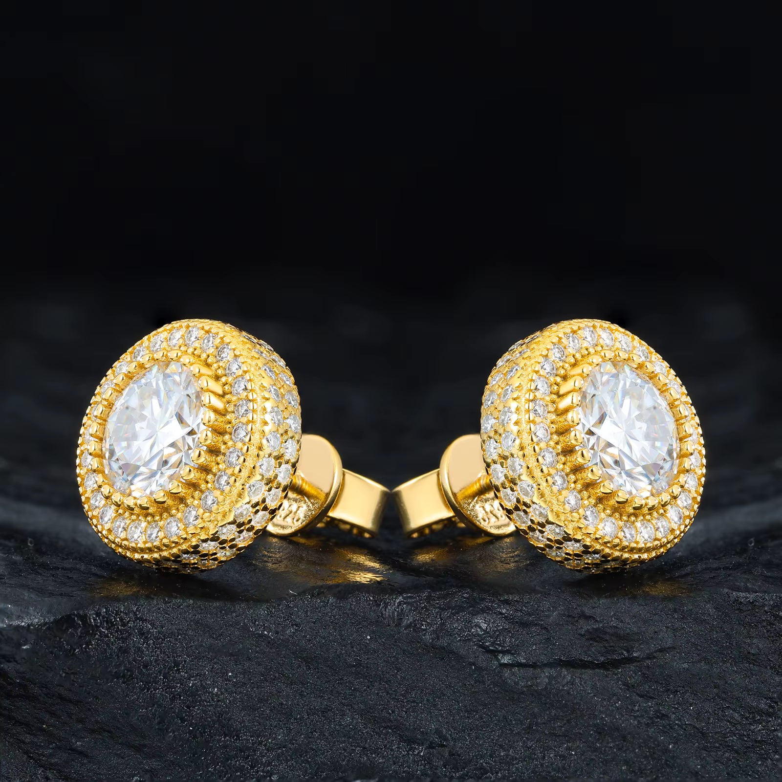 Gold cufflinks with clear gemstones on a dark surface